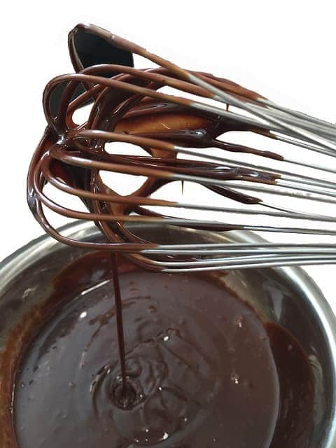 metal bowl of dark chocolate ganache with a whisk