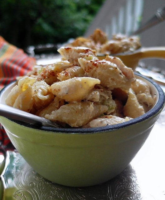 Close up shot of macaroni salad made with shells in a green bowl.