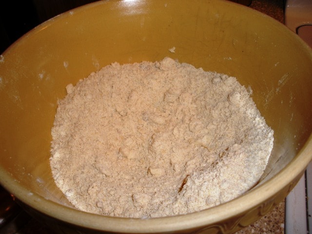 A bowl with flour in it with pieces of butter rubbed in to make pie dough.