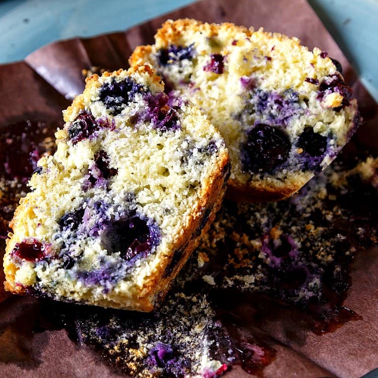 A blueberry muffin sliced in two, showing the even crumb structure and lots of blueberries.
