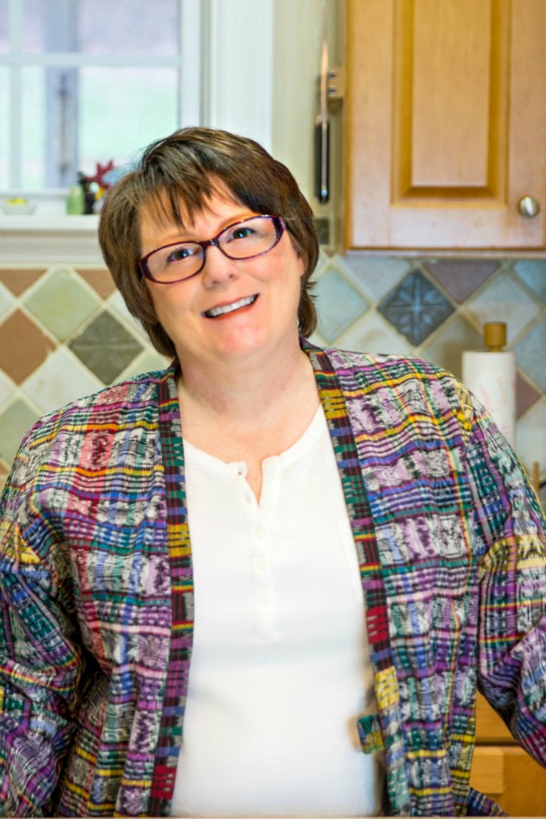 Head shot of Jenni in white shirt and multi-colored jacket.