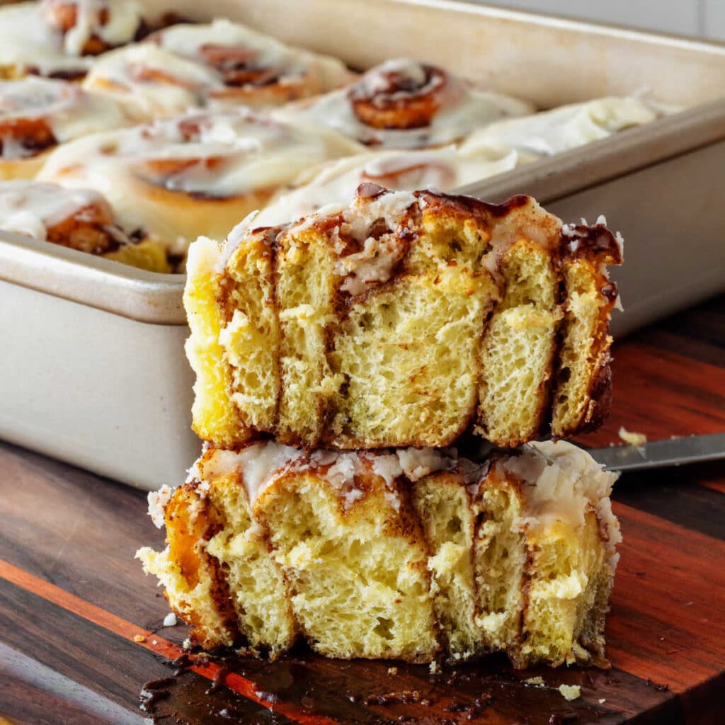 A cinnamon roll cut in half down the center with the two halves stacked on top of each other. You can see "stripes" of enriched sweet dough and gooey cinnamon filling.