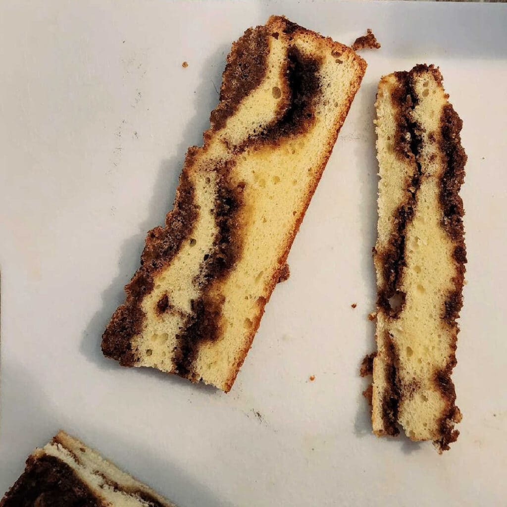 Cross-sections of two cakes, one thinner than the other. Both have streusel topping and a cinnamon filling.