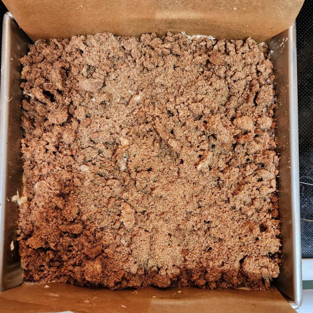 An overhead shot of a square cake with a lot of brown sugar cinnamon streusel piled on top. You cannot see the batter because the streusel covers all of it.