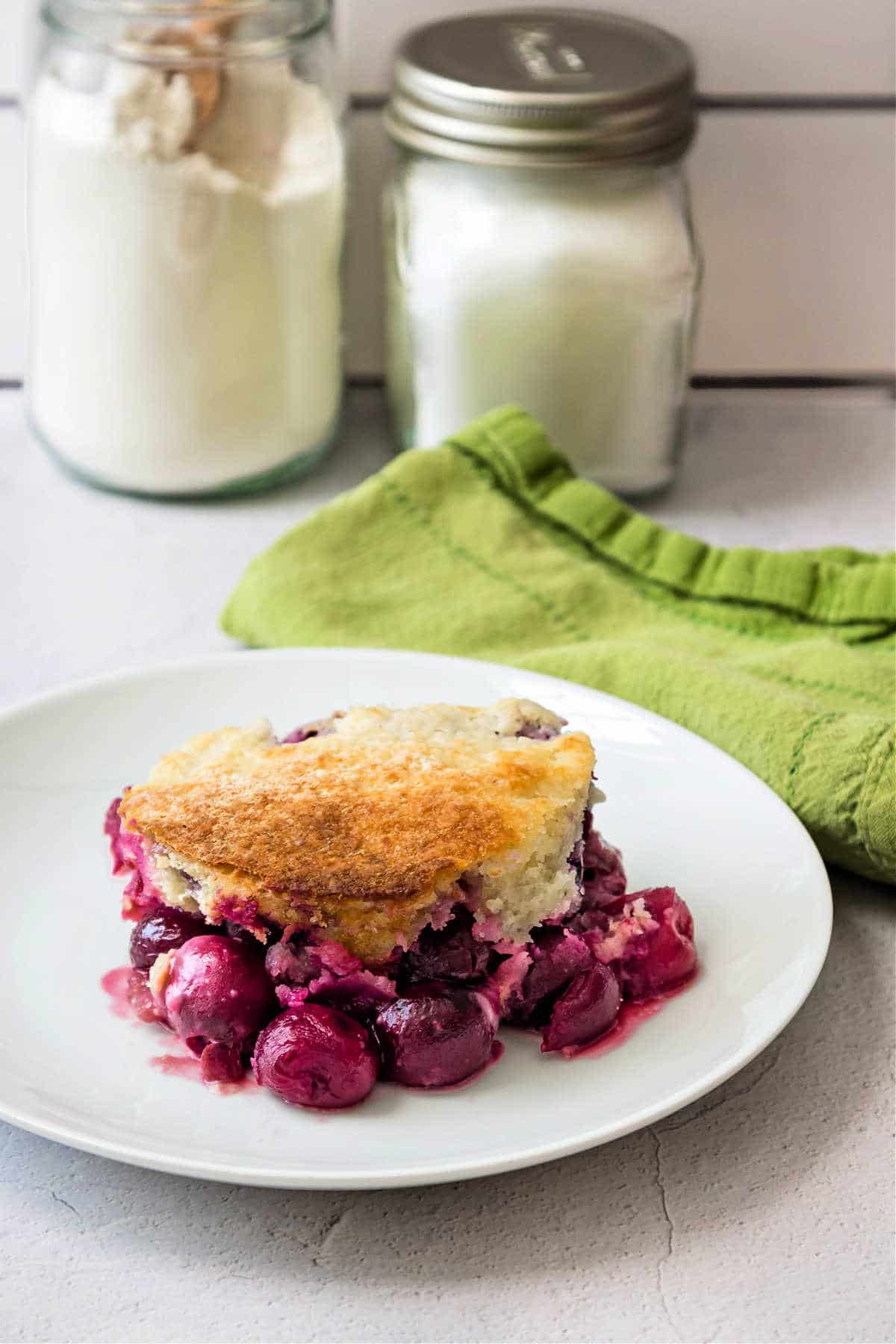 Cobble on a white plate with a jar of flour and sugar in the background.