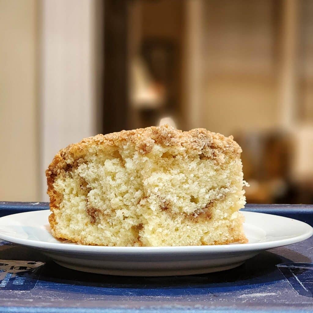 A cross-section of yellow cake with a light cinnamon ribbon running through the center and some crumbs on top.