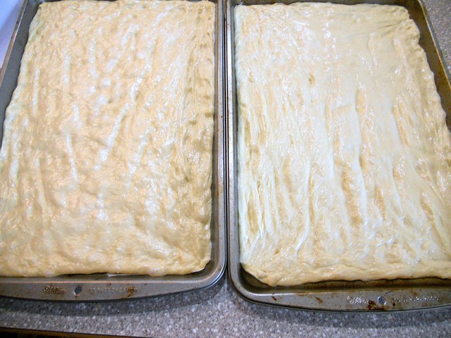 Moravian sugar cake dough in 2 rectangular baking pans ready for the oven. 