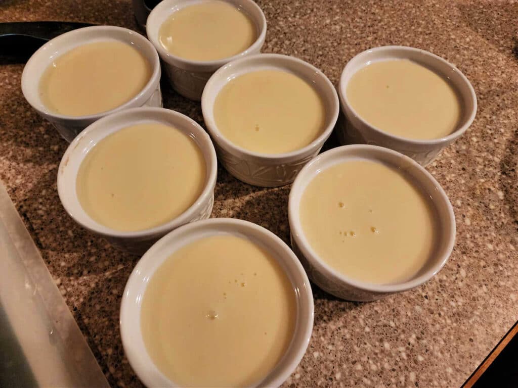 Seven round ramekins filled with pale yellow custard.