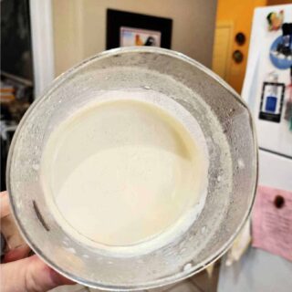 A clear plastic measuring cup help with the opening perpendicular to the floor showing how solidly thick the creme fraiche inside it is. It is not even sliding toward the opening.