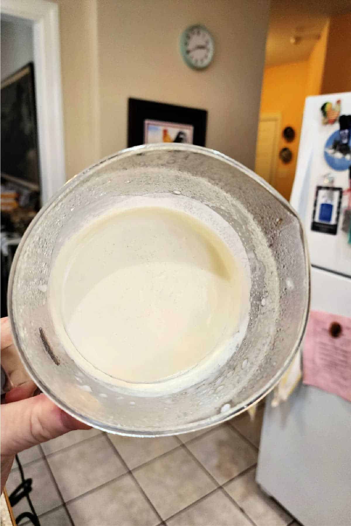 A clear plastic measuring cup help with the opening perpendicular to the floor showing how solidly thick the creme fraiche inside it is. It is not even sliding toward the opening.