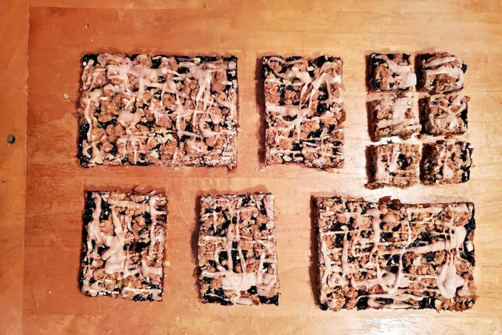 An overhead shot of cinnamon glazed bar cookies cut into different sized rectangles on a wooden cutting board.