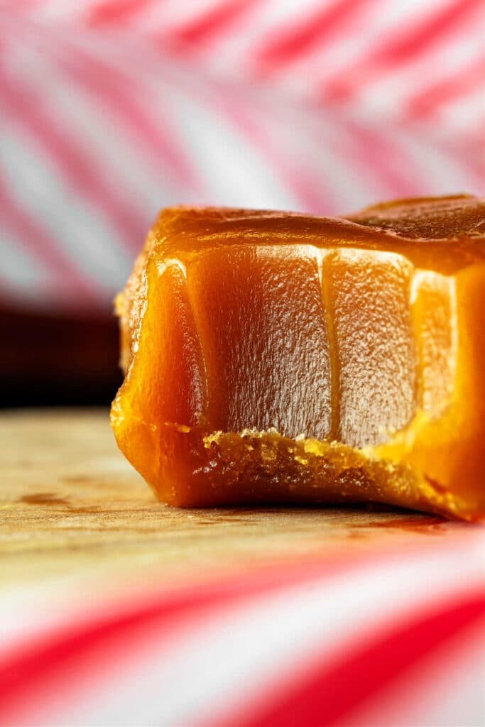 An extreme close-up of a piece of butterscotch candy with a bit taken out of it.