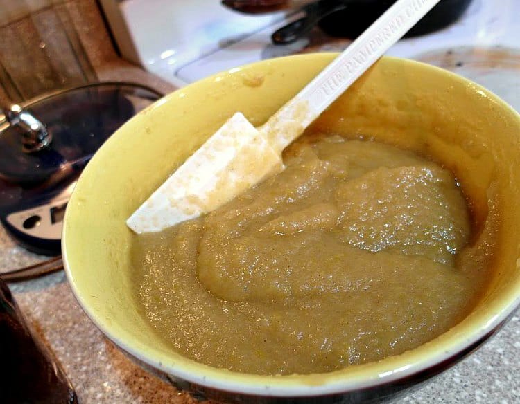A mixing bowl of Granny Smith applesauce with a white spatula in it.