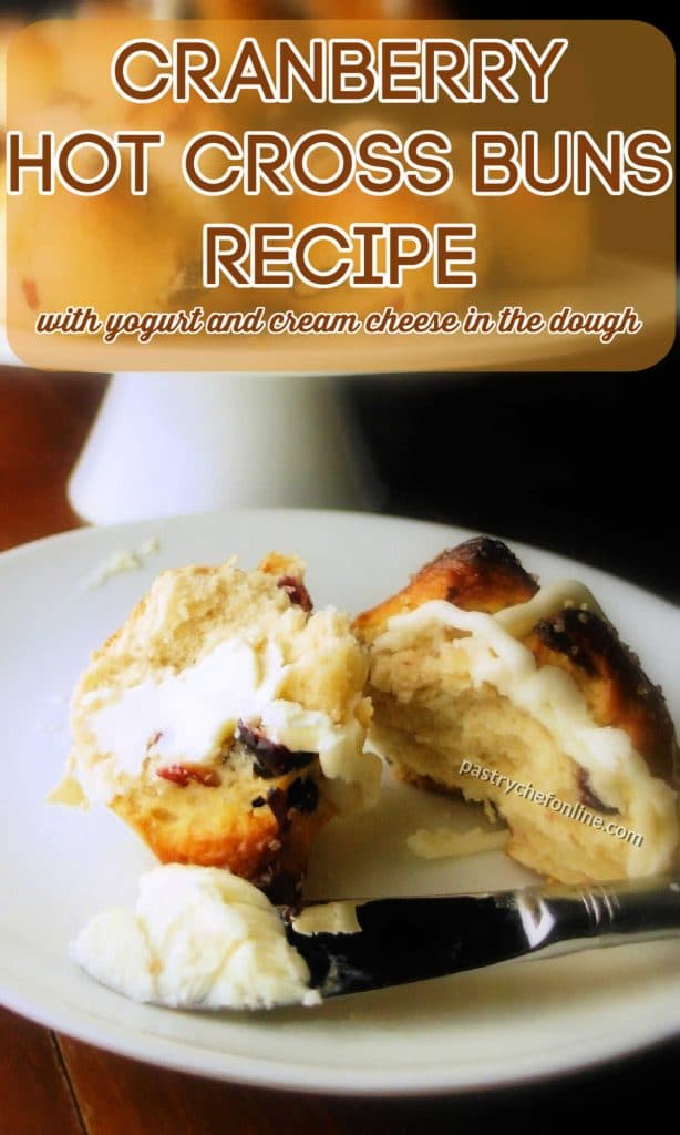Cut hot cross bun on a plate. Text reads "cranberry hot cross buns recipe with yogurt and cream cheese in the dough."