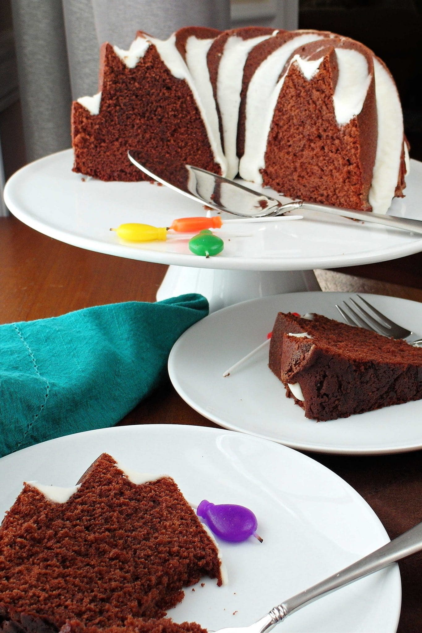 A mocha caramel pound cake on a white cake stand with two plates with slices of the cake on them.