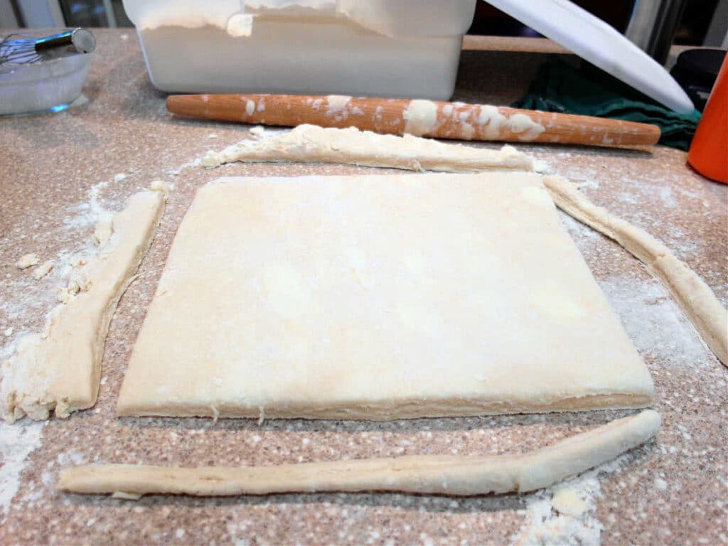 the biscuit dough rolled out to about 1/2" thick with the four sides trimmed off of ragged edges, leaving a nice rectangle of dough to cut into biscuits.