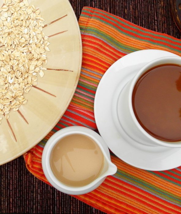 Overhead shot of coconut vanilla oat milk creamer in a white pitcher with a cup of coffee and a plate of oatmeal.