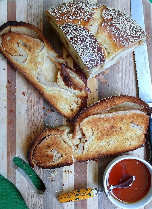 overhead shot of a bread board with sliced and toasted challah bread with sesame seess on top