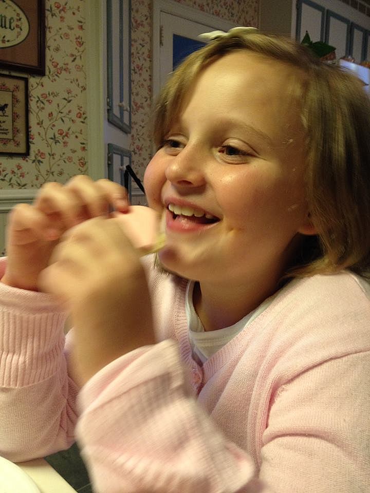 A smiling girl eating a sugar cookie.