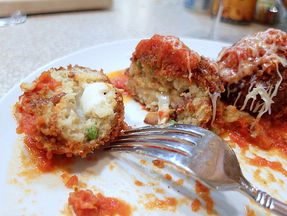 Cut open Pea and Bacon arancini, showing melted cheese inside.