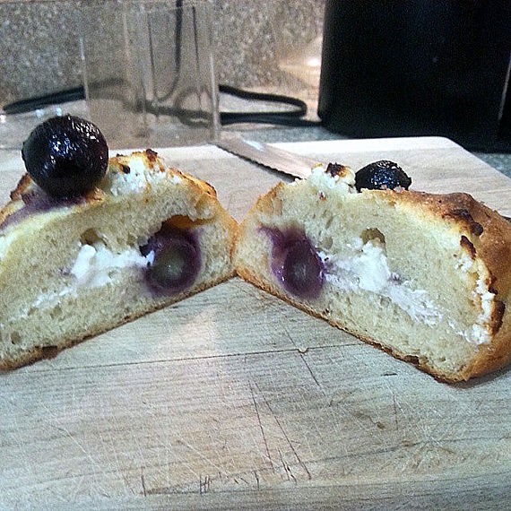 The interior of a roll stuffed with goat cheese, lemon zest, and fresh grapes.
