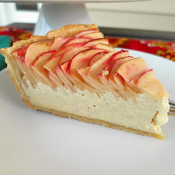 A side view of a slice of apple chai cheesecake tart on a white plate.