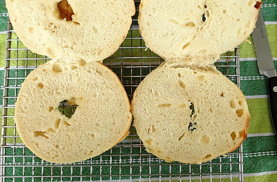 Cheese bagels sliced open so you can see the interior. The bagel on the left is the results of 5 hours of rising. The right is after 15 hours. The longer rise resulted in a chewier texture.