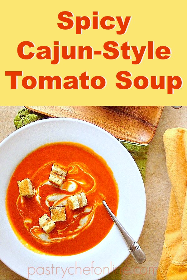 pin image for cajun spicy tomato soup bowl of soup with croutons. text reachs "spicy cajun-style tomato soup: