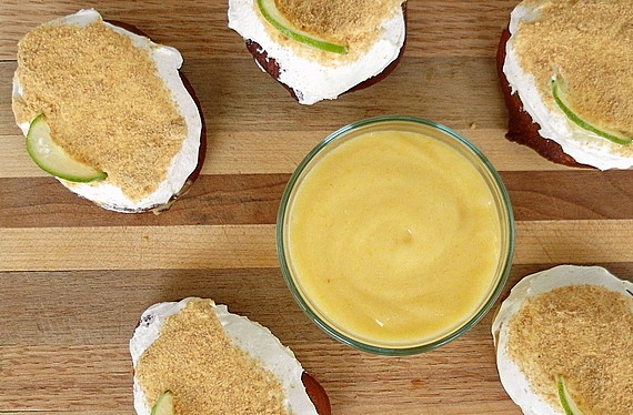 Overhead view of 5 key lime pie doughnuts  on a board around a bowl of key lime curd.