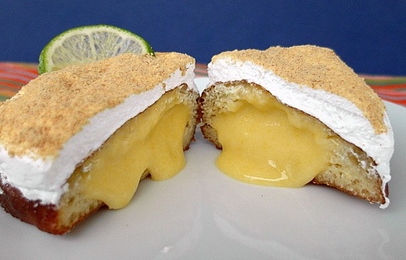 A sliced open key lime pie doughnut showing curd on the inside.