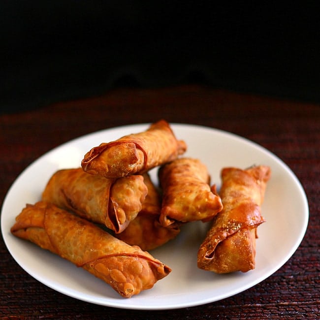 3/4 view of crispy egg rolls on a white plate.