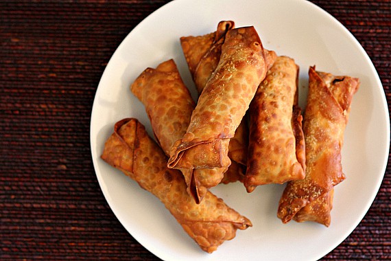 Overhead view of fried egg rolls on a white plate.