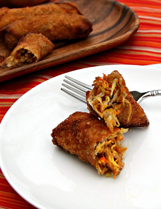 An egg roll cut open to show the spicy pork filling inside.
