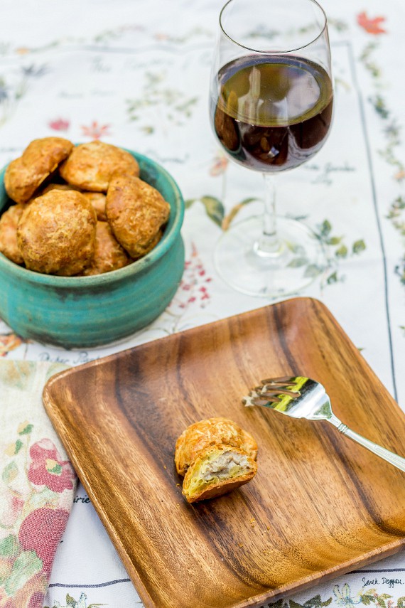 a cut open gougere on a plate and a bowl of gougeres