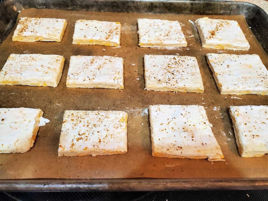 Twelve rectangles of dough spaced out on a parchment-lined baking sheet, ready to go in the oven.