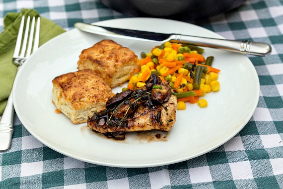 A dinner plate with a serving of chicken thighs, biscuits, and vegetables.
