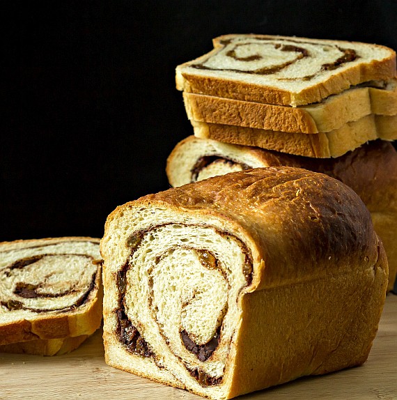 a sliced loaf of cinnamon raisin swirl bread with stacked up slices