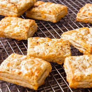 A close-up image of square cheese biscuits cooling on a cooling rack.