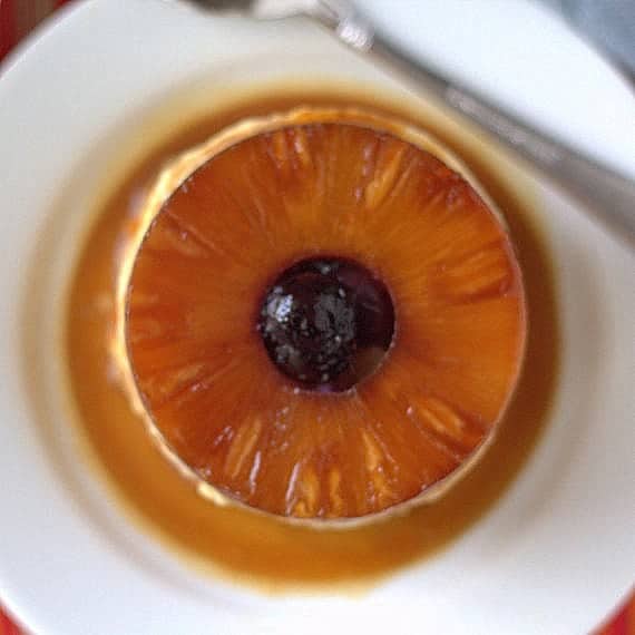 overhead shot of an individual pineapple cheesecake with a pineapple ring and a cherry on top