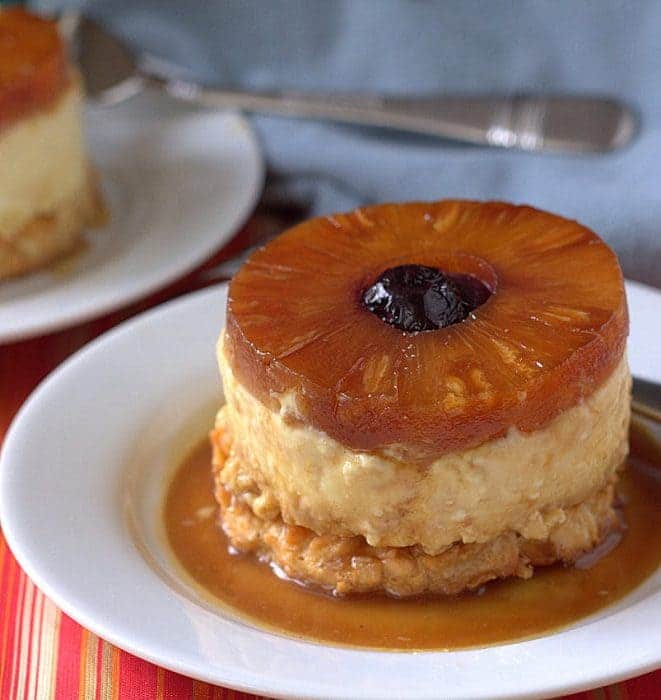 an individual pineapple upside down cheesecake with a ring of pineapple on top and a cherry in the center