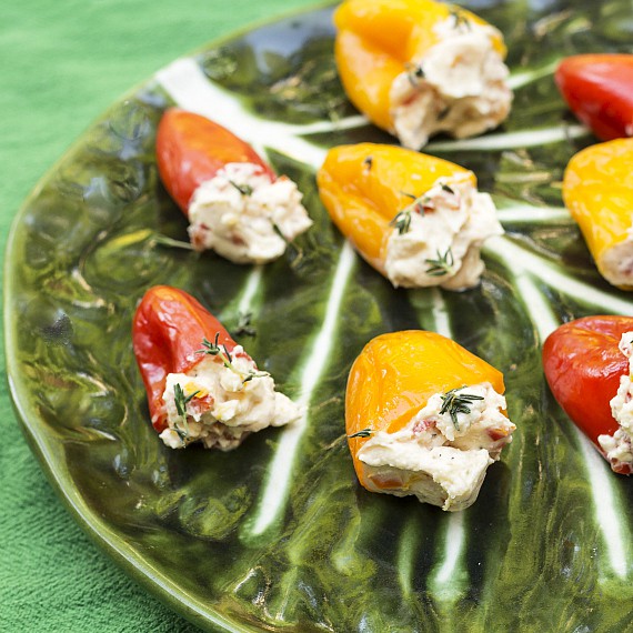 Tangy Pickled Peppers Stuffed with Herbed Goat Cheese on a green cabbage leaf design glass platter.