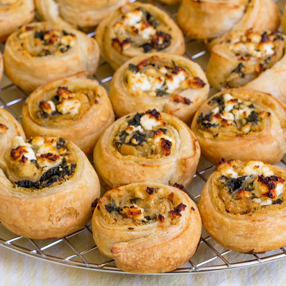 Close up of hummus puff pastry pinwheels cooling on a rack.