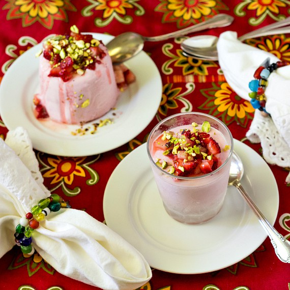 2 strawberry kulfi on plates with spoons.