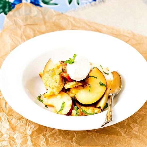 A bowl of peach panzanella with a spoon.
