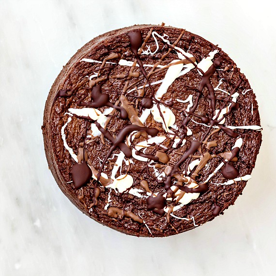 Overhead shot of a 6" double chocolate cheesecake splattered with dark, milk, and white chocolate.