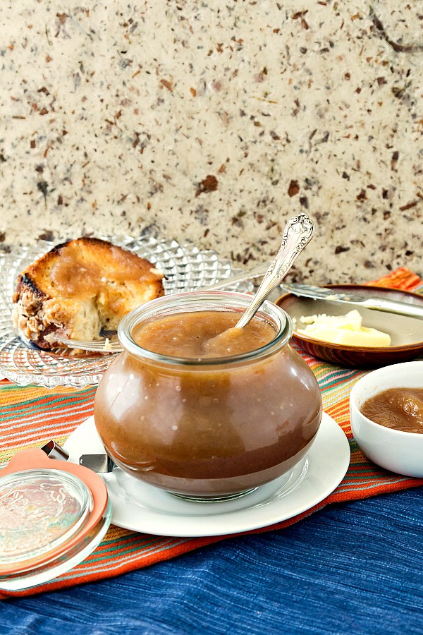 A jar of apple butter on a white plate.