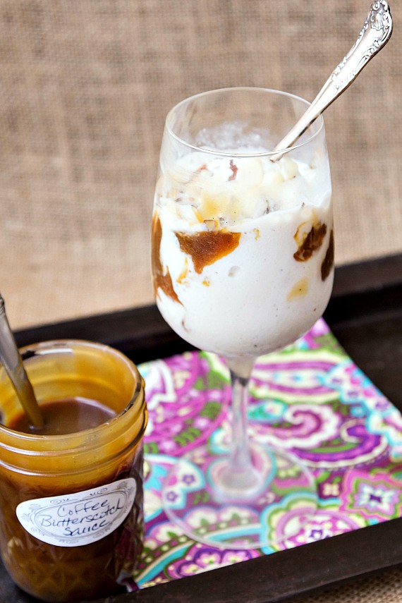 Wine glass of ice cream with coffee butterscotch sauce and jar of sauce next to it.