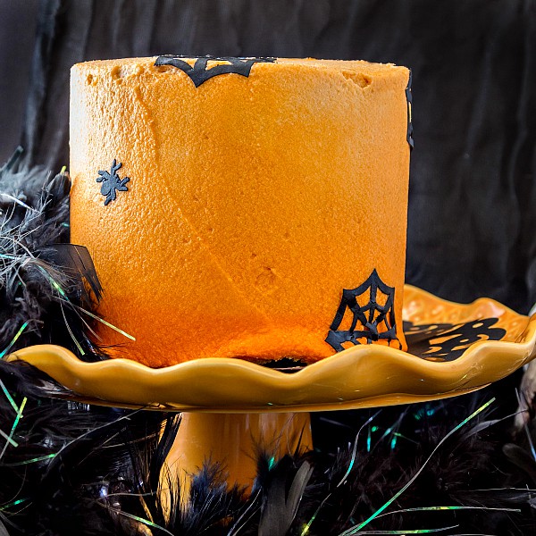 A 3 layer chocolate cake frosted with orange frosting and decorated for Halloween.