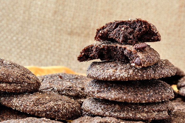 A stack of chocolate cookies with one broken in half to show the fudgy insides.