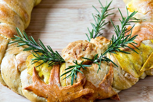 Close up of the pinecone, leaf decoration in dough and rosemary sprigs on a decorative Thanksgiving bread.